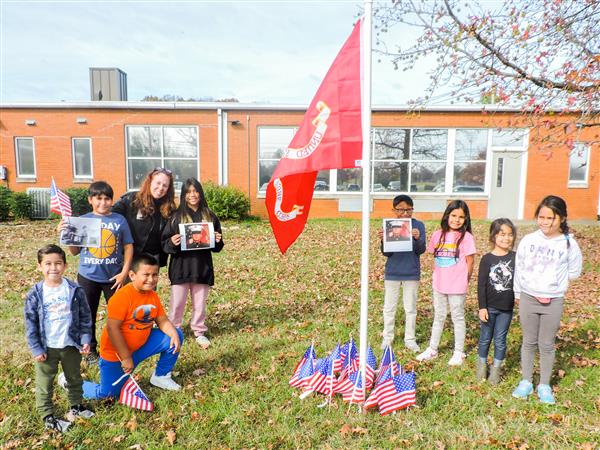 Students holding up homemade signs for a Veterans Day celebration.